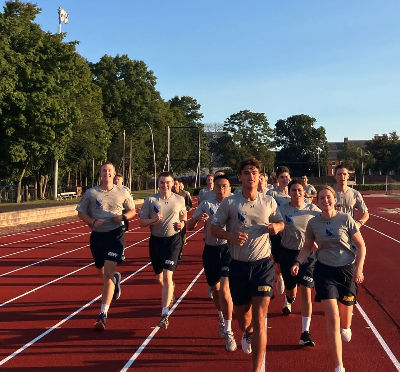 Midshipmen running on a track in their physical training uniforms.