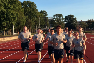 Midshipmen running on a track in their physical training uniforms.
